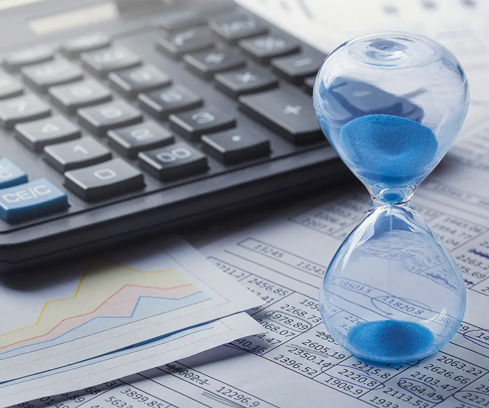 Hourglass, financial charts and calculator on a table.